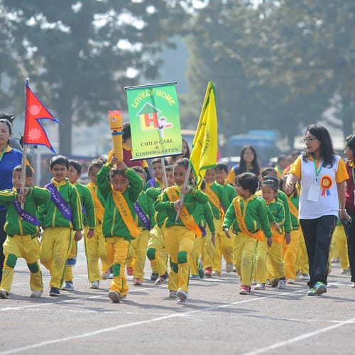 Lovely Home students carrying the Nepal flag and school banner in a parade
